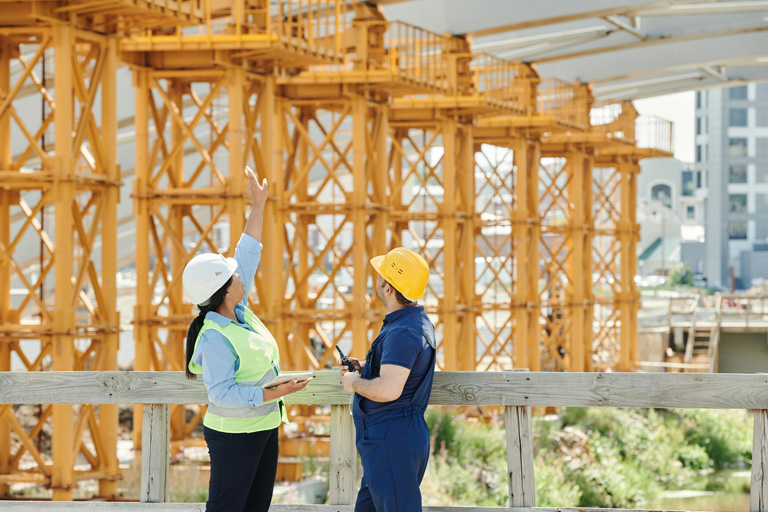 Dos profesionales con casco de seguridad supervisando una estructura metálica