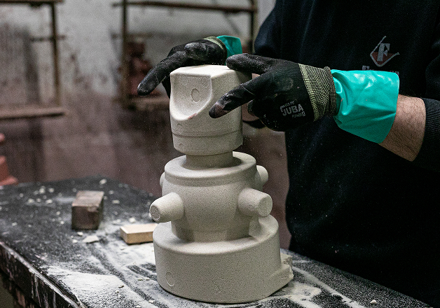 Artesano trabajando en escultura de piedra con guantes protectores